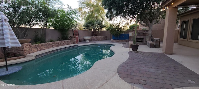 view of swimming pool featuring a fenced in pool, a patio, a fenced backyard, and an outdoor stone fireplace