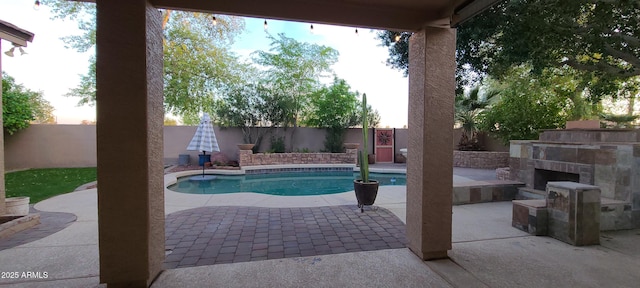view of pool featuring a patio, a fenced backyard, a fenced in pool, and exterior fireplace