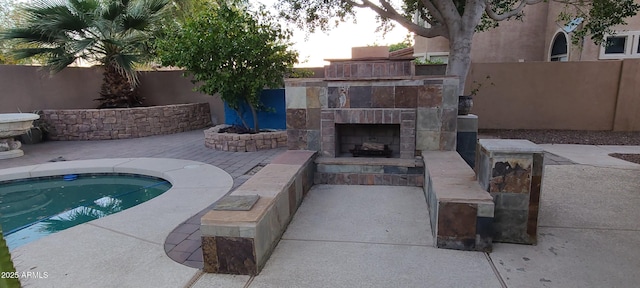 view of pool featuring exterior fireplace, a patio area, and fence