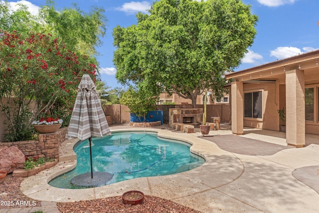 view of pool with a fenced backyard, an outdoor stone fireplace, and a patio