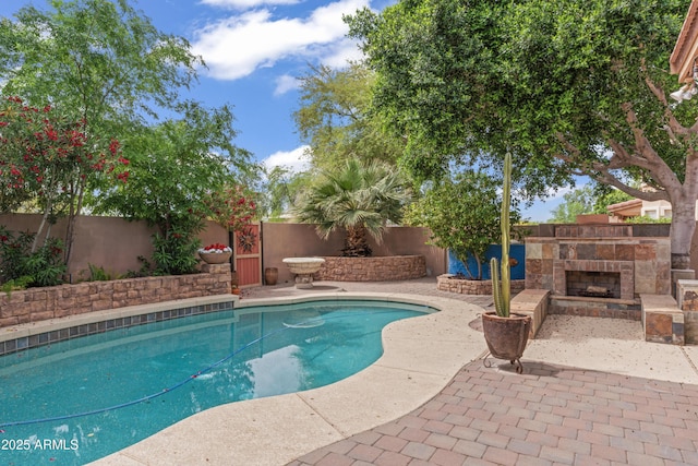 view of pool featuring a fenced in pool, a patio, a fenced backyard, and an outdoor stone fireplace