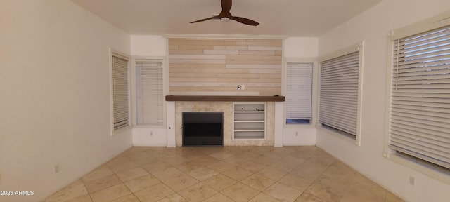 unfurnished living room featuring a fireplace, light tile patterned floors, and ceiling fan