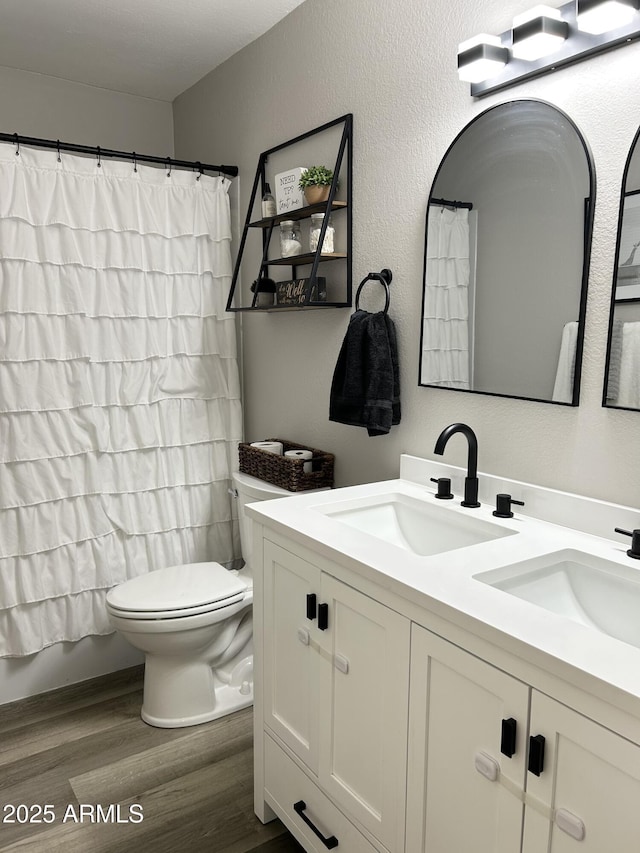 full bathroom with double vanity, toilet, wood finished floors, and a sink