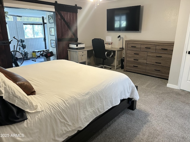 bedroom with a barn door, baseboards, and carpet flooring