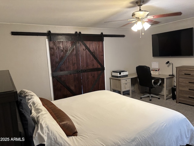 carpeted bedroom with a ceiling fan and a barn door