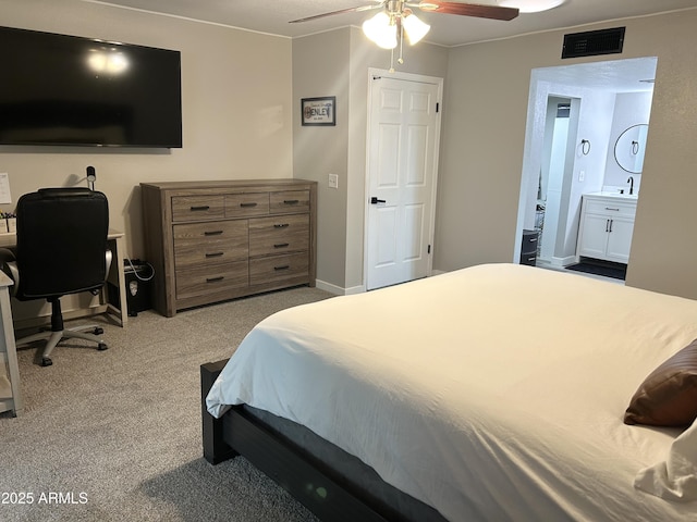 carpeted bedroom with a ceiling fan, baseboards, visible vents, a sink, and ensuite bathroom