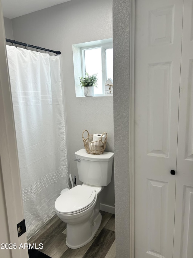 bathroom with a shower with shower curtain, toilet, and wood finished floors