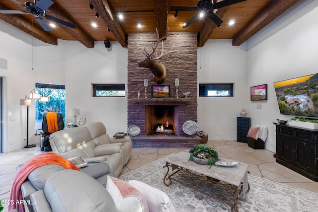 living room featuring beam ceiling, ceiling fan, a high ceiling, a fireplace, and wood ceiling