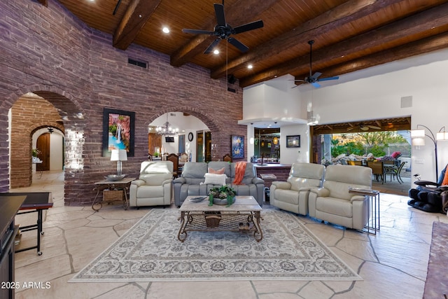 living room featuring ceiling fan with notable chandelier, beam ceiling, a towering ceiling, and wooden ceiling