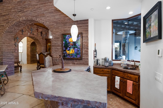 bar with pendant lighting, sink, and brick wall