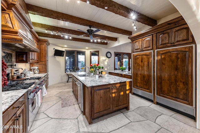 kitchen with light stone countertops, appliances with stainless steel finishes, decorative backsplash, ceiling fan, and an island with sink