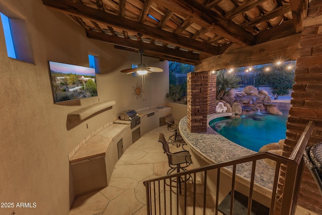 view of pool with an outdoor kitchen, ceiling fan, and a grill