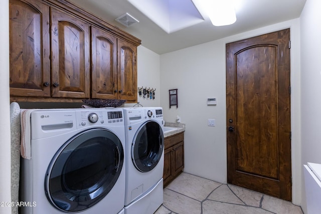 laundry area featuring washing machine and clothes dryer, light tile patterned floors, and cabinets