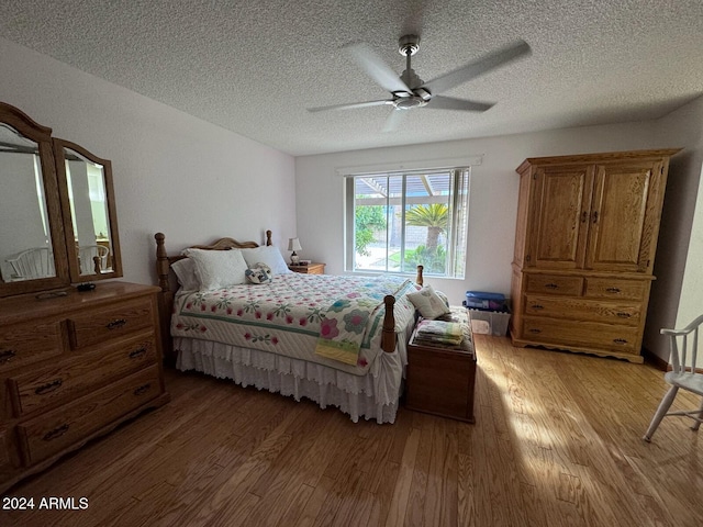 bedroom with ceiling fan, light hardwood / wood-style floors, and a textured ceiling