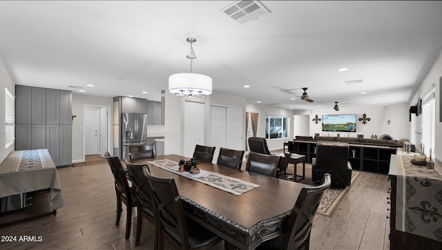 dining space with ceiling fan with notable chandelier and light hardwood / wood-style floors