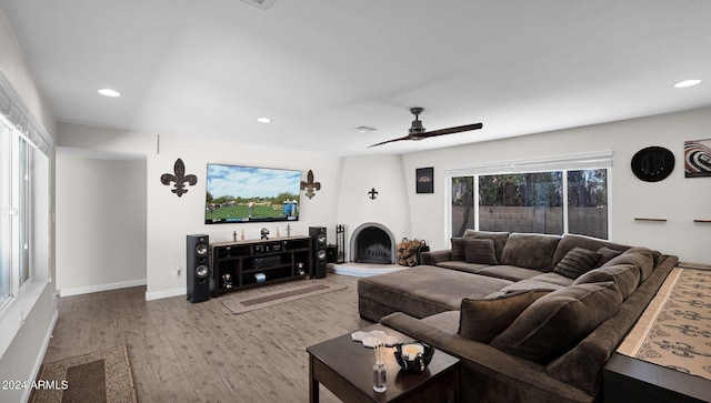 living room featuring a fireplace, ceiling fan, and light hardwood / wood-style flooring