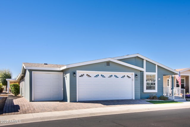 ranch-style home featuring decorative driveway and an attached garage