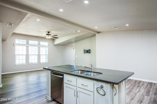 kitchen featuring dark countertops, dishwasher, open floor plan, and a sink