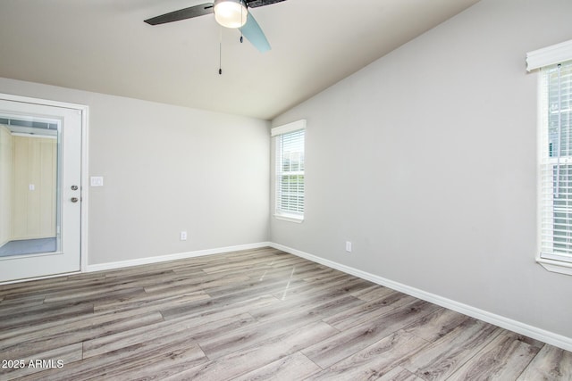 spare room with vaulted ceiling, ceiling fan, wood finished floors, and baseboards