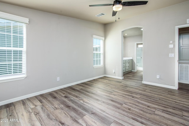 spare room with arched walkways, visible vents, and wood finished floors