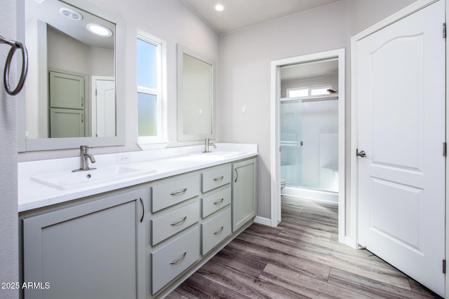 full bath featuring double vanity, a sink, toilet, and wood finished floors