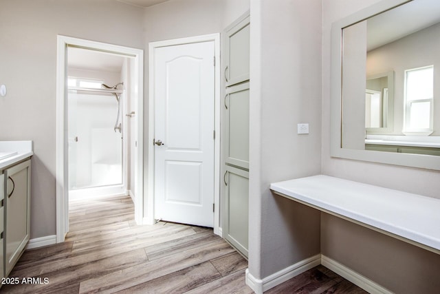 full bathroom with a shower, vanity, baseboards, and wood finished floors