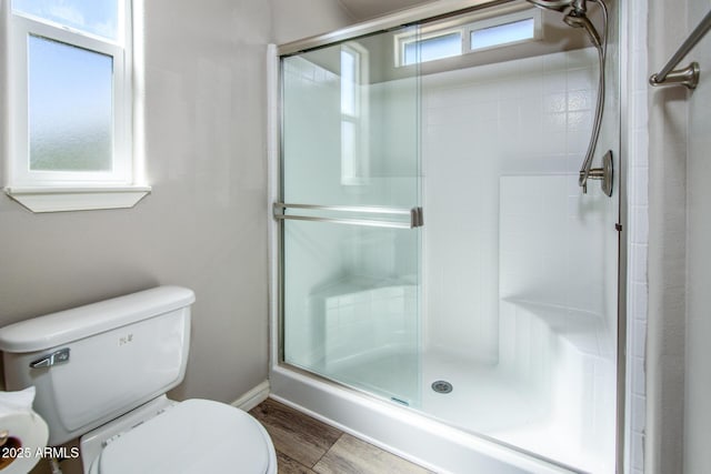 bathroom featuring a stall shower, baseboards, toilet, and wood finished floors