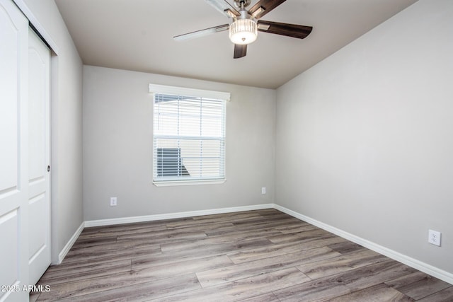 spare room featuring wood finished floors, a ceiling fan, and baseboards