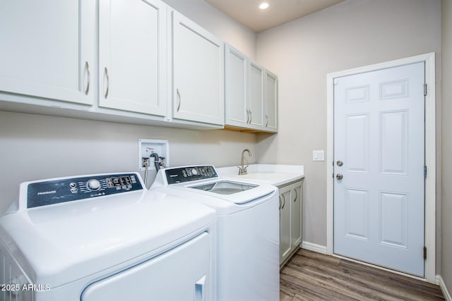 clothes washing area featuring cabinet space, baseboards, wood finished floors, separate washer and dryer, and a sink