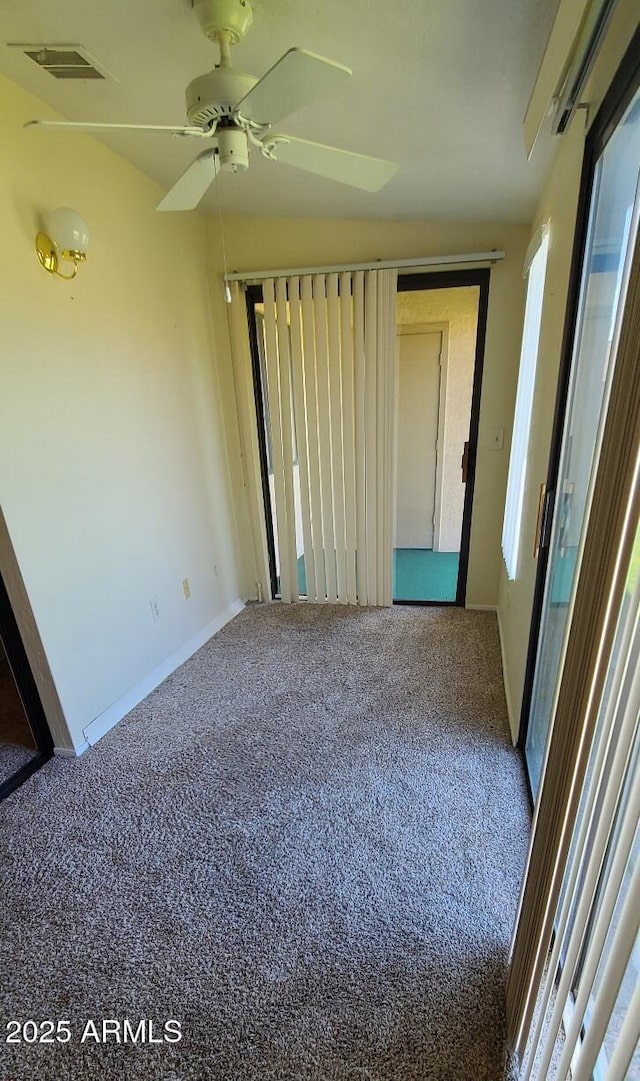 spare room featuring carpet floors, ceiling fan, visible vents, and baseboards