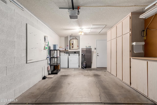 garage featuring water heater, washing machine and clothes dryer, concrete block wall, and a garage door opener