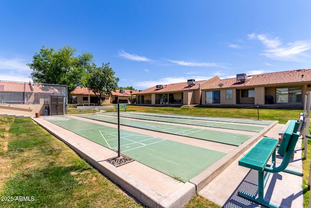 view of home's community with shuffleboard, fence, and a lawn
