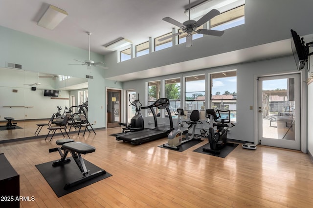 gym with visible vents, ceiling fan, plenty of natural light, and a towering ceiling