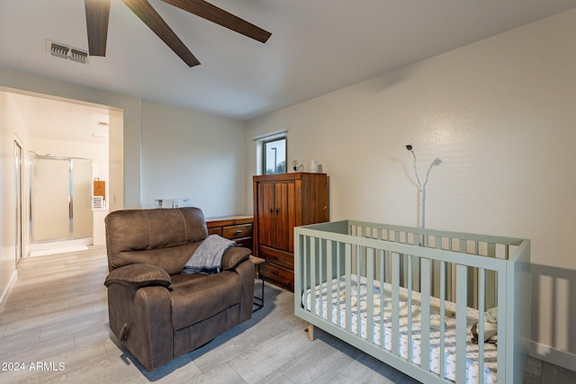 bedroom featuring ceiling fan, light wood-type flooring, and a crib