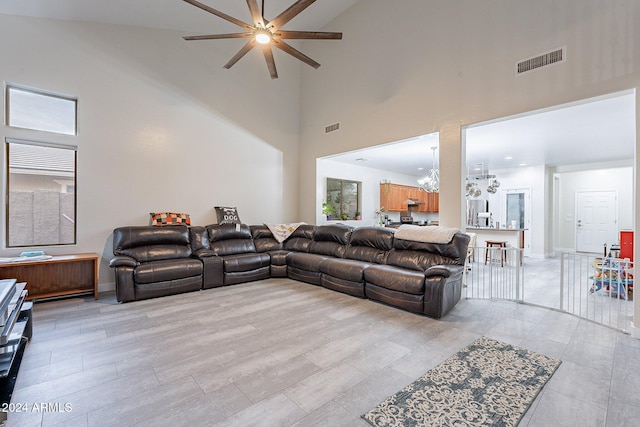 living room with ceiling fan with notable chandelier and high vaulted ceiling