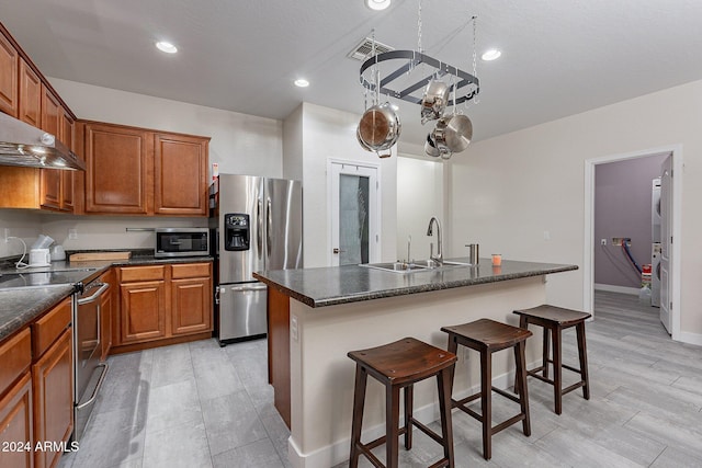 kitchen featuring sink, a breakfast bar area, stainless steel appliances, extractor fan, and an island with sink