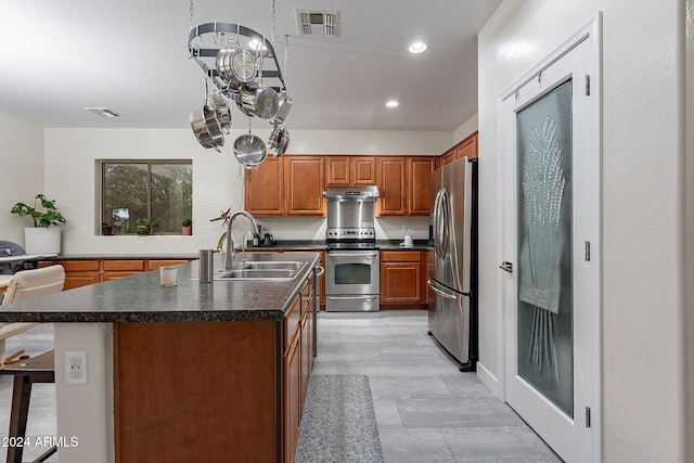 kitchen with appliances with stainless steel finishes, a breakfast bar, range hood, sink, and a center island with sink