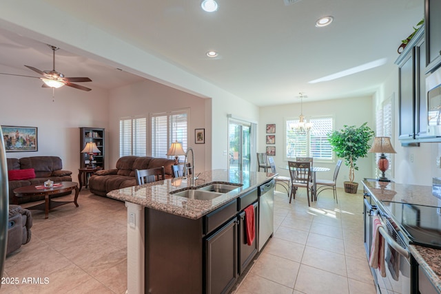 kitchen featuring hanging light fixtures, sink, light stone counters, an island with sink, and stainless steel appliances