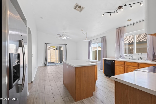 kitchen with a center island, sink, ceiling fan, stainless steel fridge, and black dishwasher