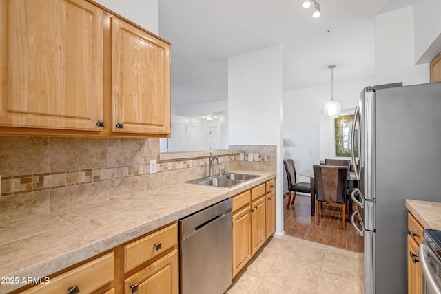 kitchen with decorative light fixtures, tasteful backsplash, sink, light tile patterned flooring, and appliances with stainless steel finishes