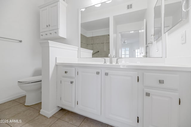 bathroom featuring toilet, tile patterned floors, tiled shower, and vanity