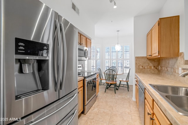 kitchen featuring decorative light fixtures, backsplash, sink, light tile patterned flooring, and appliances with stainless steel finishes