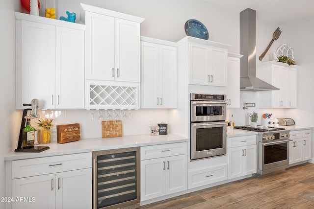 8523 N 192nd Ave, Waddell, AZ 85355 - kitchen with wall chimney exhaust hood, beverage cooler, stainless steel appliances, tasteful backsplash, and white cabinetry
