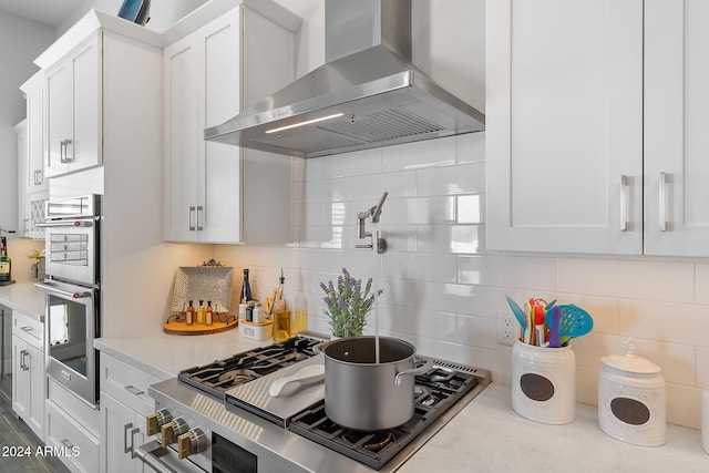 8523 N 192nd Ave, Waddell, AZ 85355 - kitchen featuring wall chimney exhaust hood, white cabinetry, backsplash, stainless steel double oven, and stovetop with downdraft