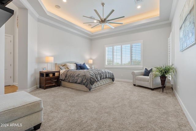 carpeted bedroom with a raised ceiling, ceiling fan, and ornamental molding