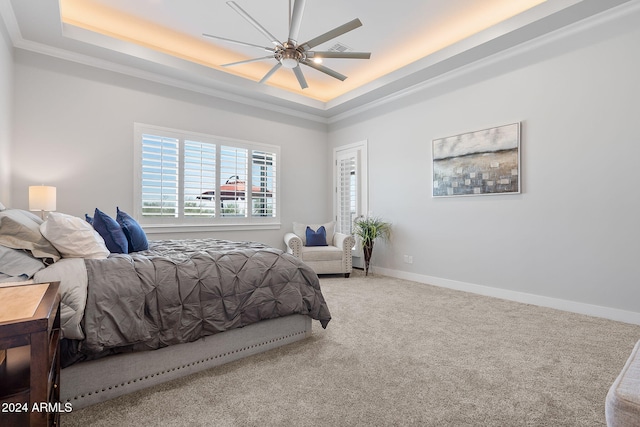 carpeted bedroom featuring ceiling fan, crown molding, and a tray ceiling