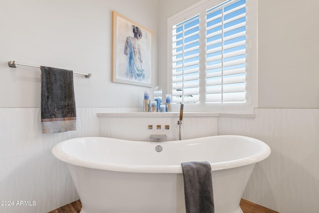 bathroom featuring a bathing tub, tile walls, and a wealth of natural light