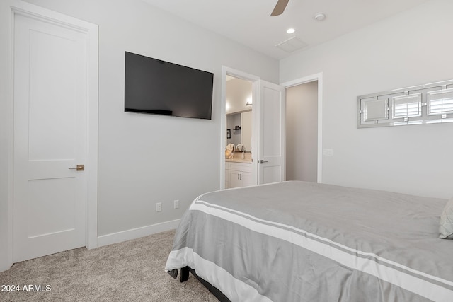 bedroom with ceiling fan, ensuite bathroom, and light carpet