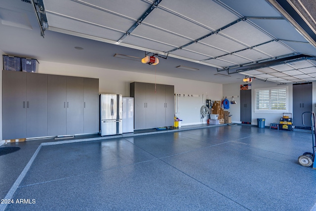 garage featuring a garage door opener, stainless steel refrigerator, and a carport