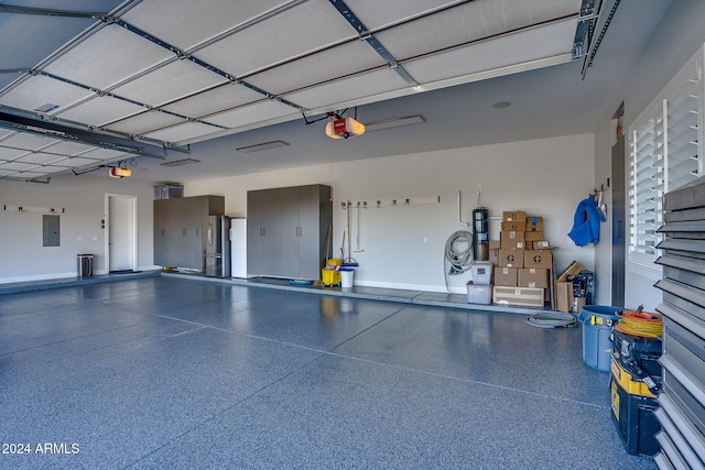 garage with stainless steel fridge, electric panel, and a garage door opener